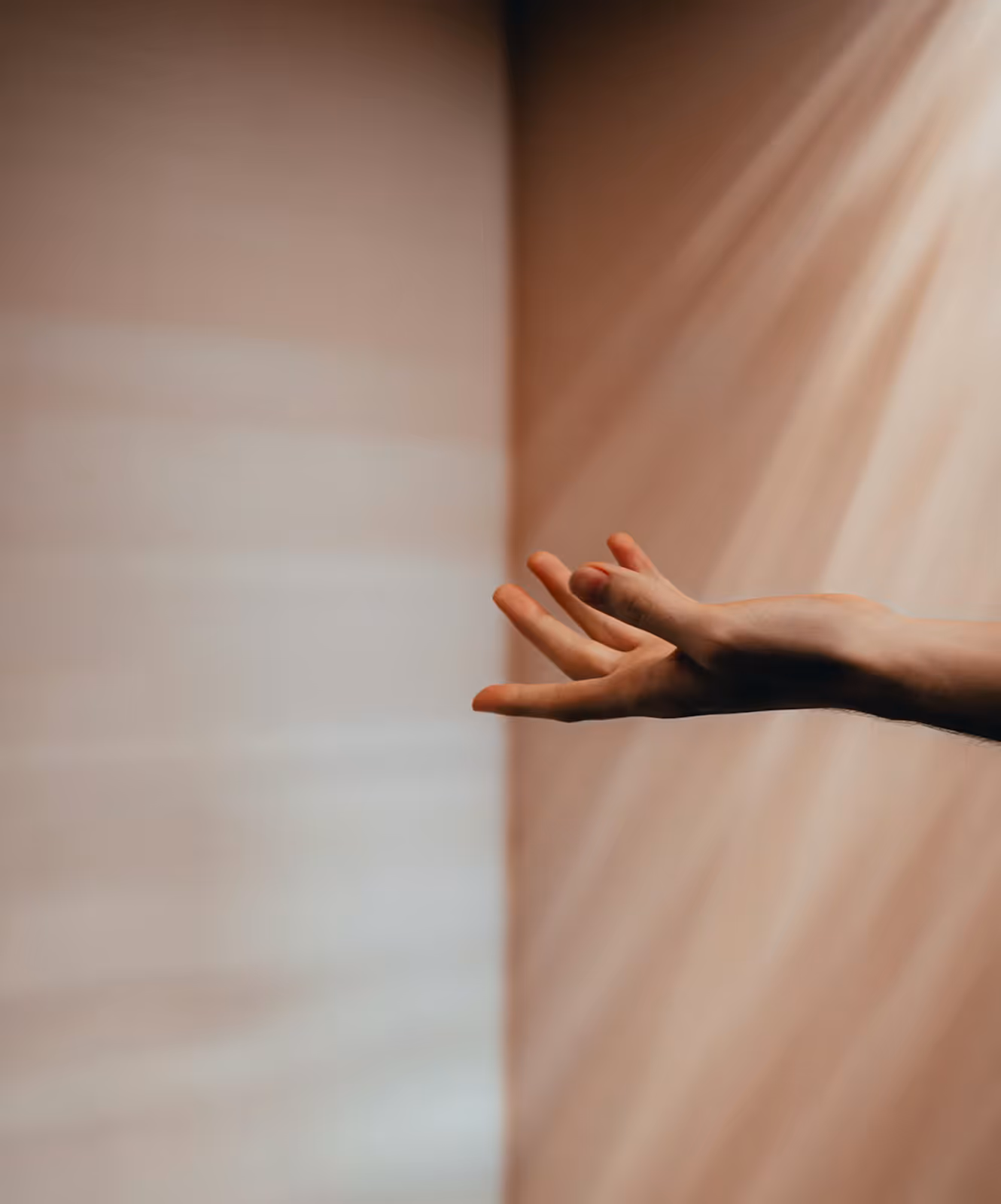 A right hand reaching out with fingers slightly spread against a soft gradient background with warm light rays.
