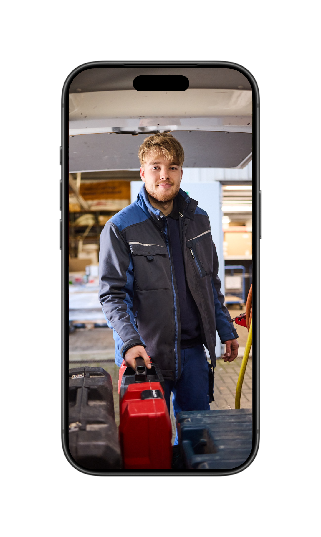 Smartphone mit Foto eines jungen Buse-Mitarbeiters, der im Werkstattwagen Werkzeugkoffer bereitstellt.