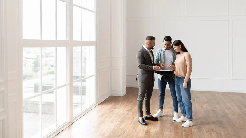 agent immobilier faisant visiter un appartement à un couple