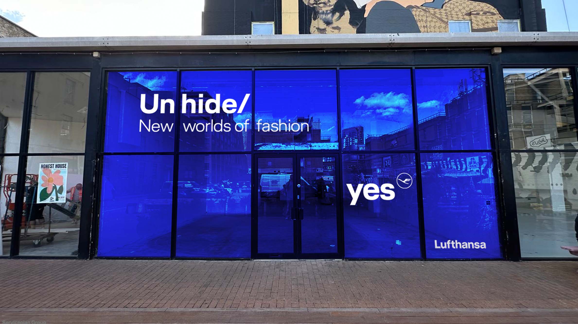 Lufthansa Unhide New Worlds storefront at Truman Brewery with blue-lit windows and campaign branding during London Fashion Week
