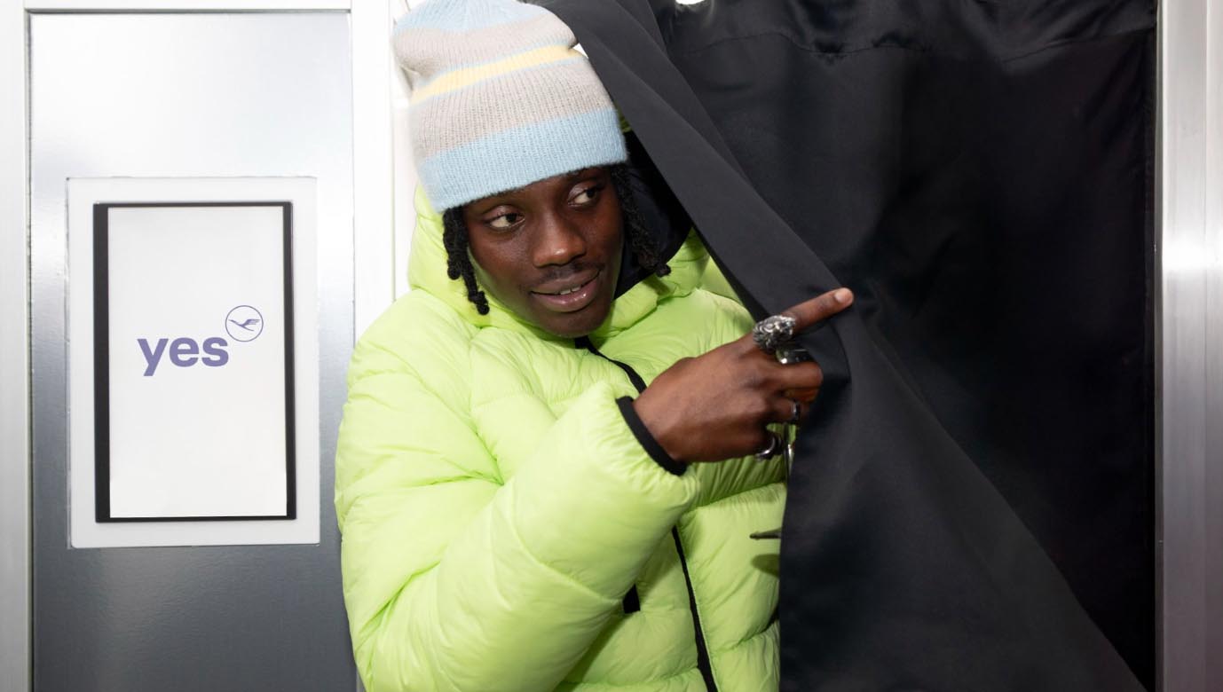 Visitor in neon yellow puffer jacket interacting with airport-inspired installation at Lufthansa Unhide New Worlds pop-up, Truman Brewery