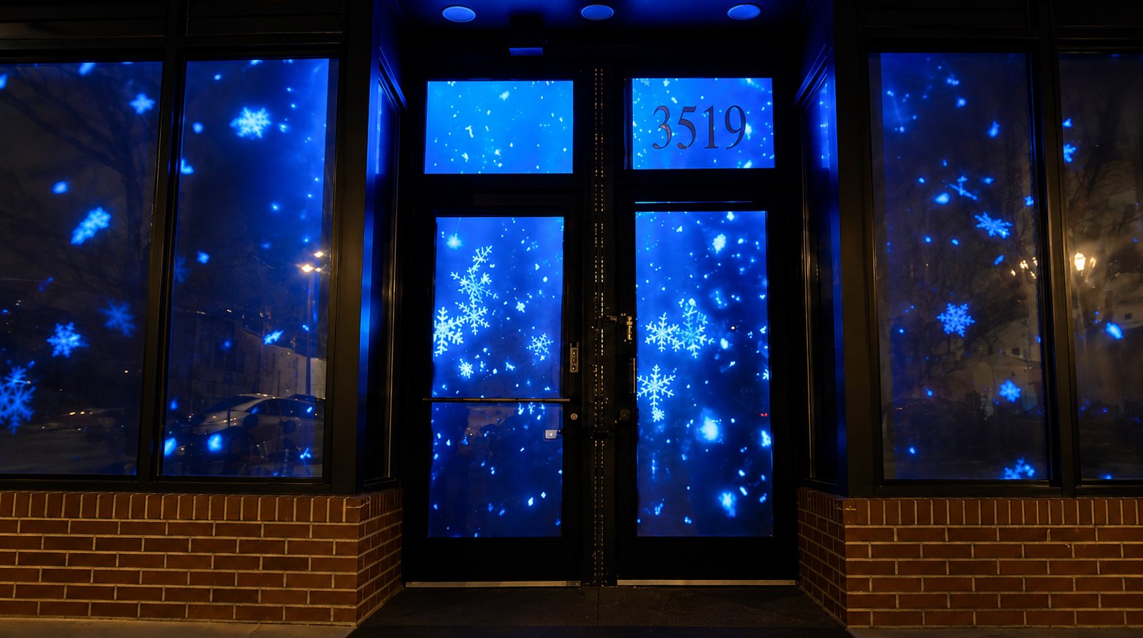 Snowflake projection filling a storefront window and door after dark