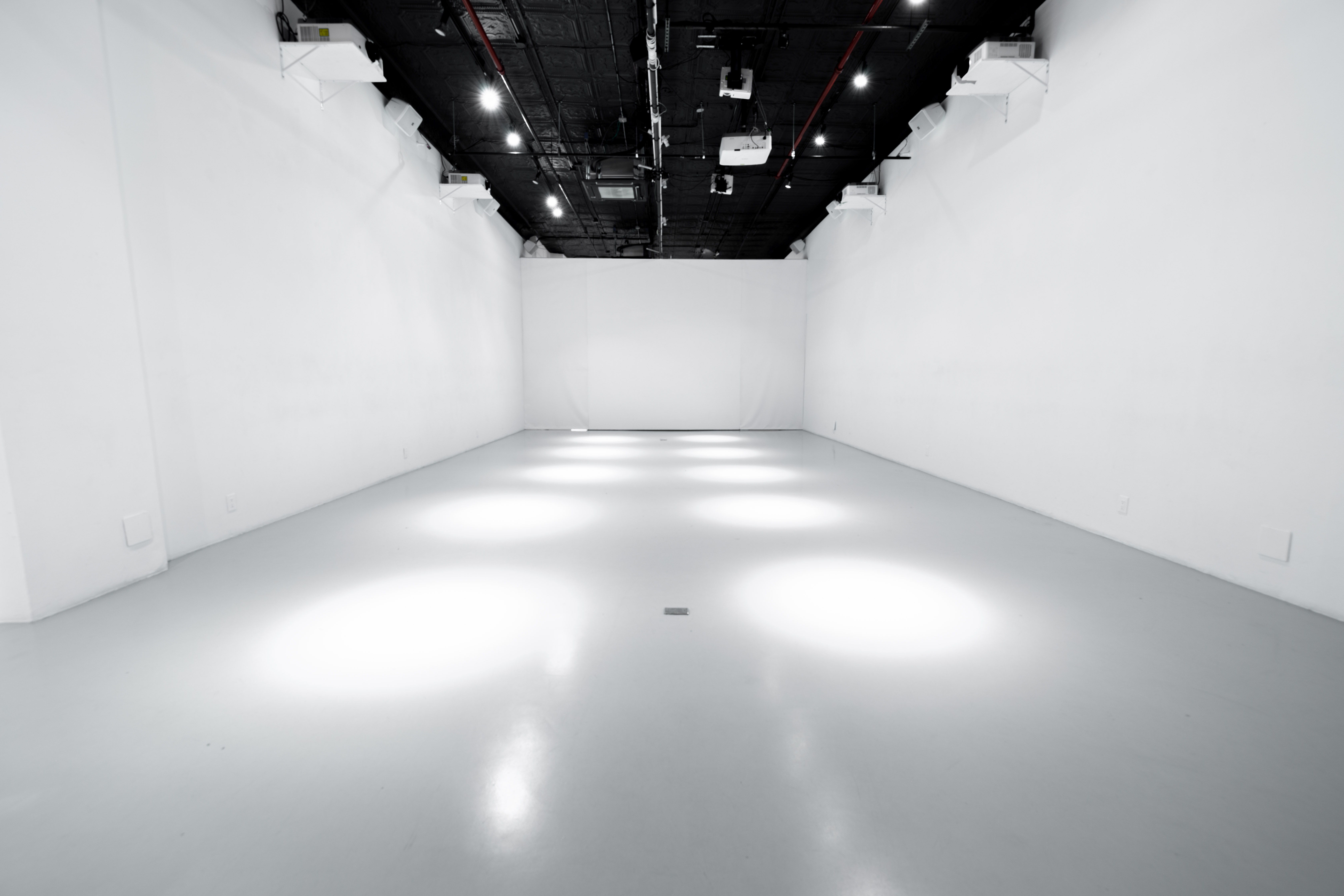Empty Immersive Studio with white walls, polished floor, and ceiling mounted projectors