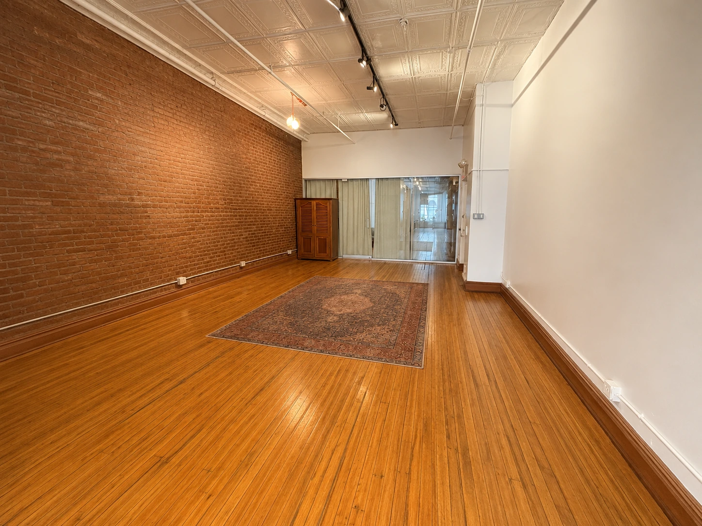 Empty loft with exposed brick, hardwood floors, and tin ceiling at LUME Studios