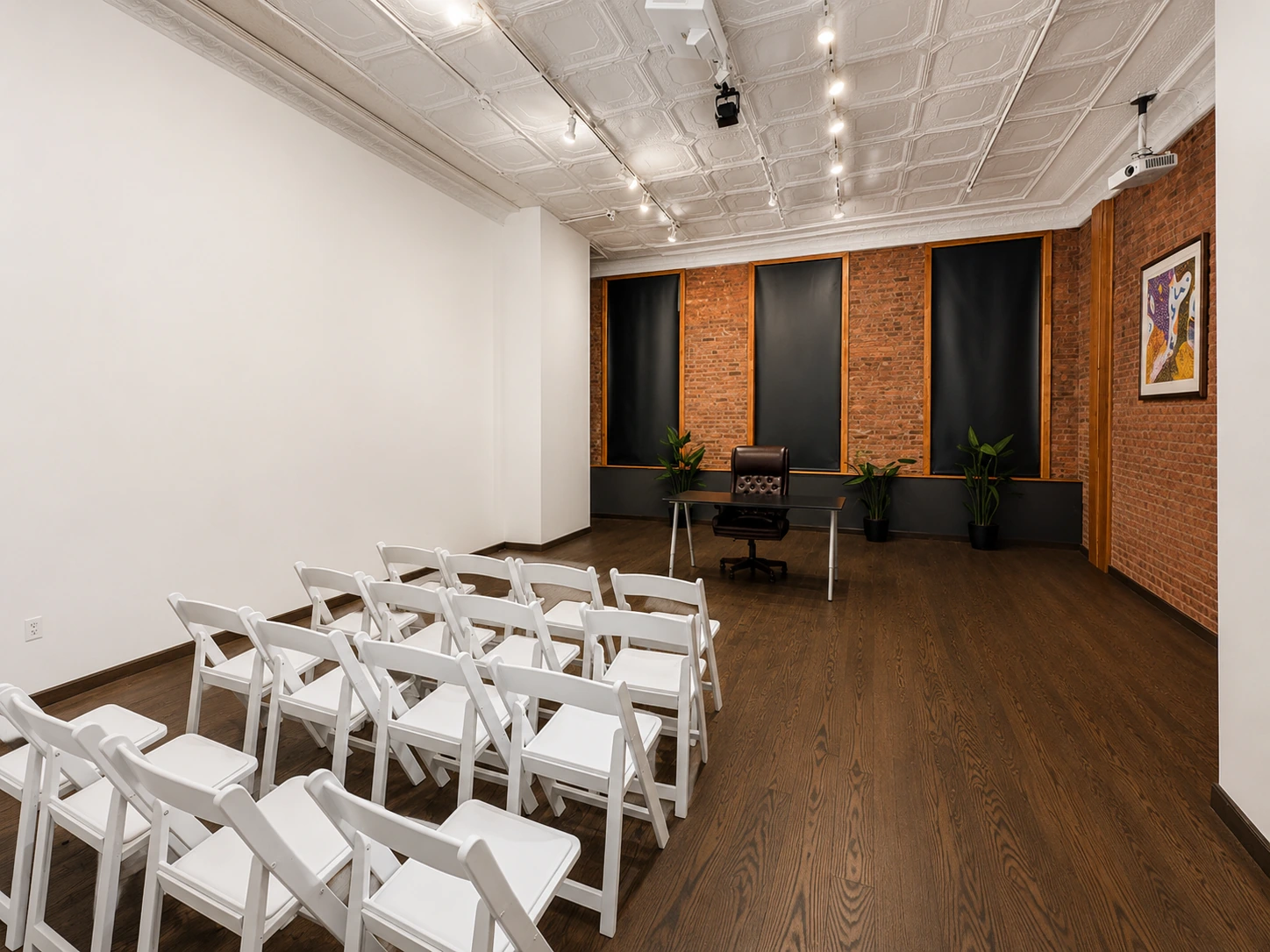 Rows of white folding chairs facing a presenter table against brick walls in Loft 2 at LUME Studios