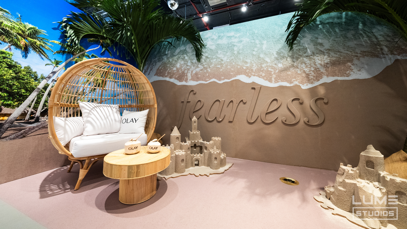Beach themed Olay set with rattan chair, sandcastles, and fearless written in sand at LUME Studios