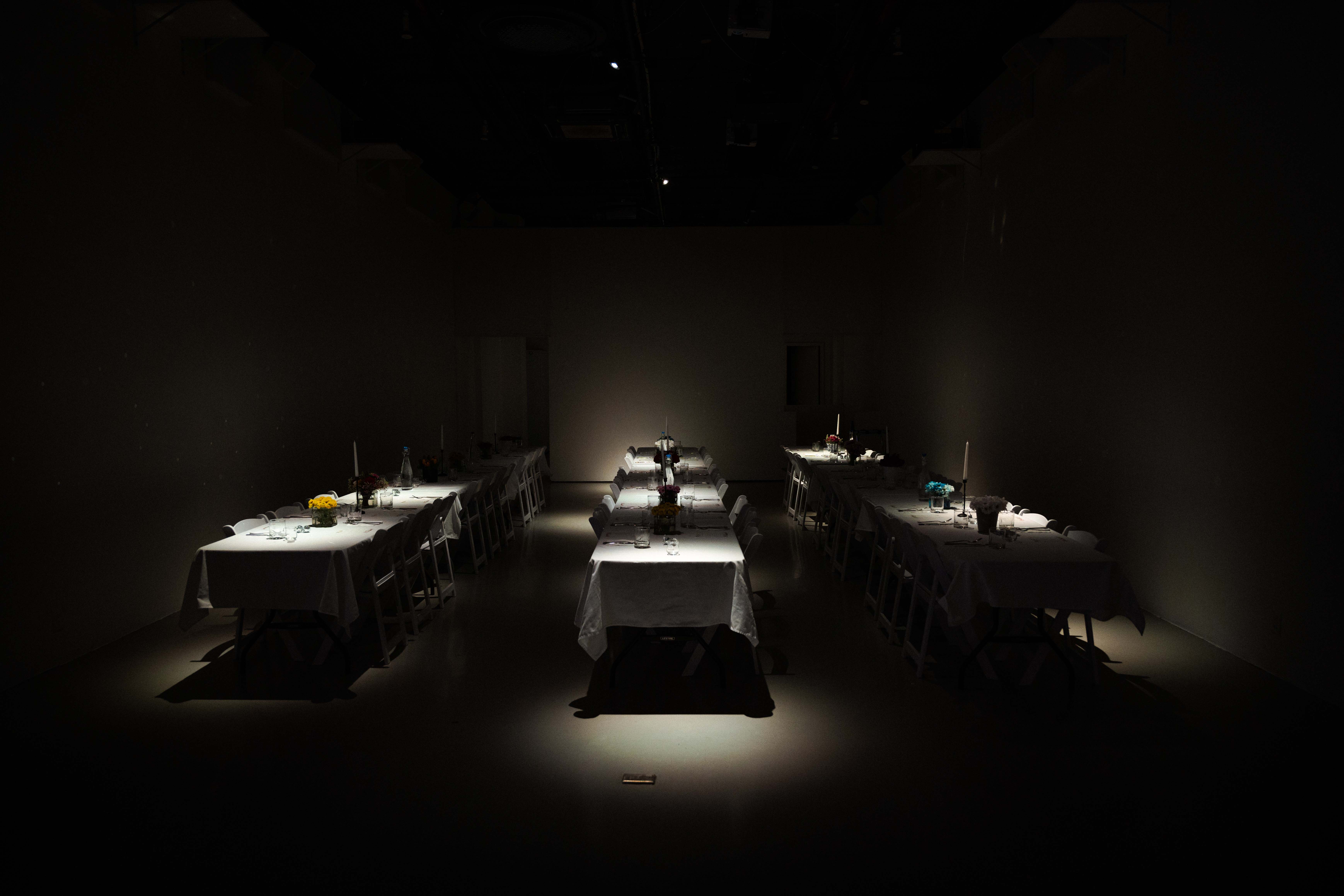 Dim spotlit dinner tables set for The Dinner Table event at LUME Studios