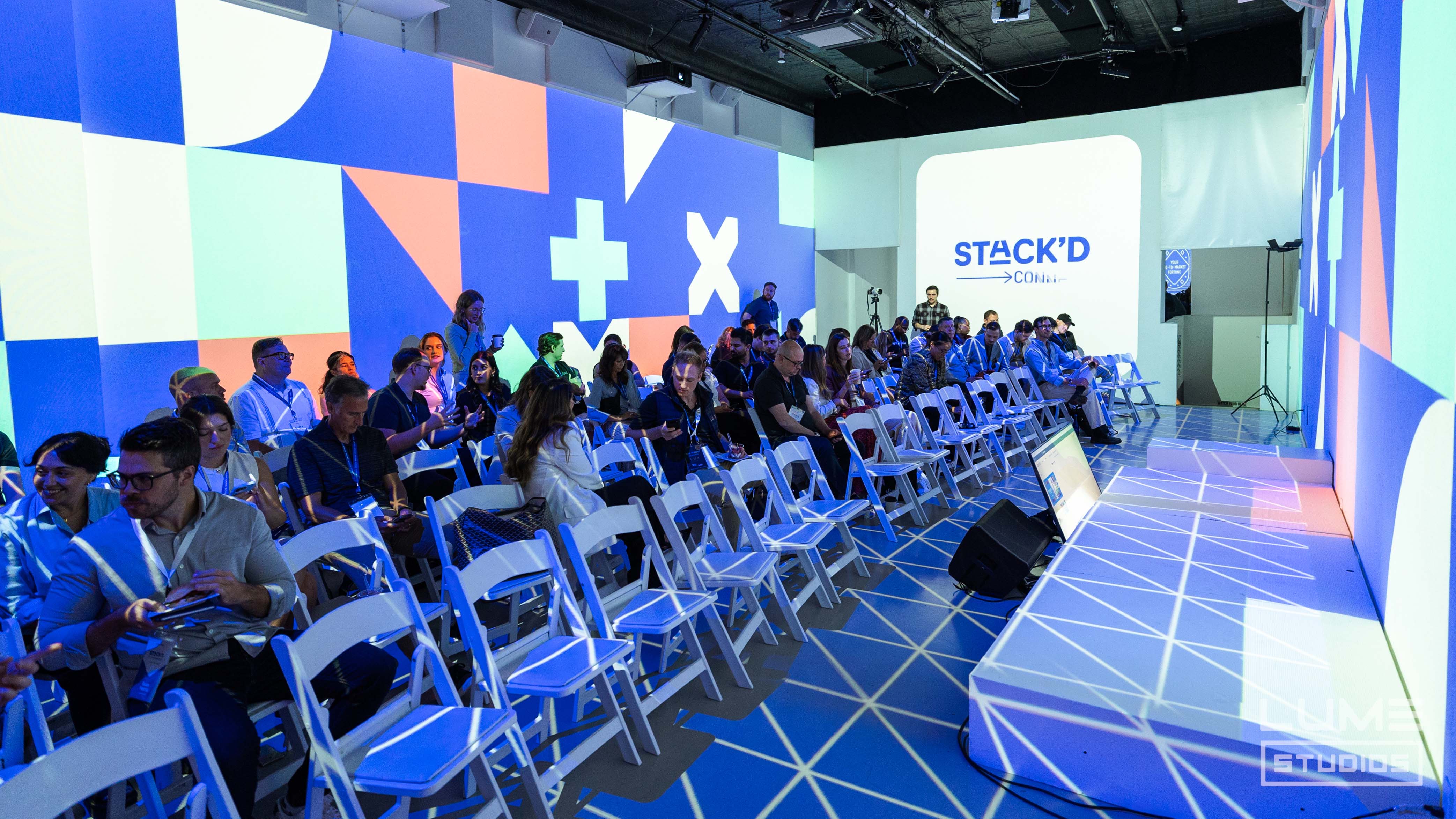 Audience seated for a conference with geometric wall graphics projected around the room