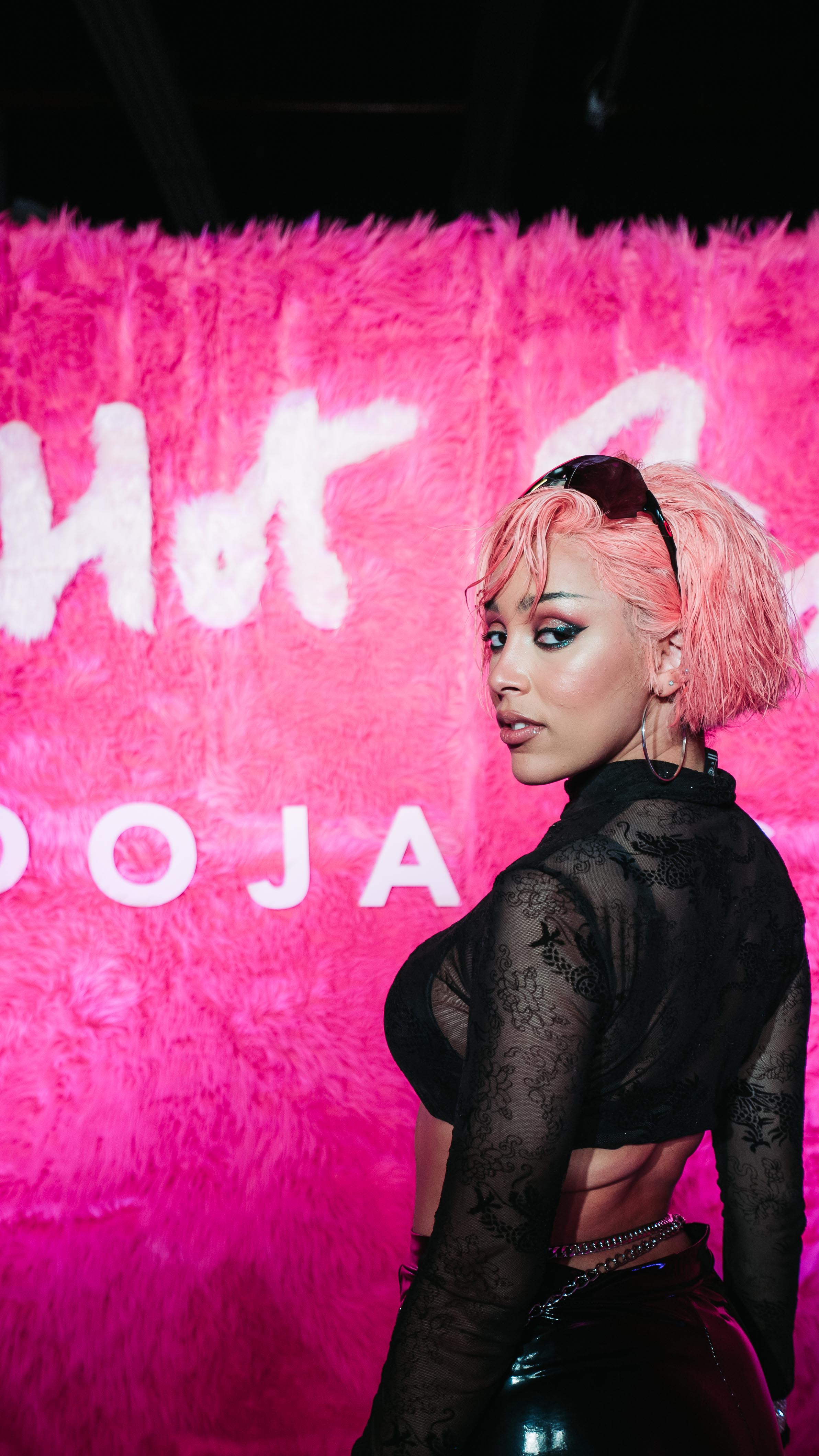 Doja Cat with pink hair in front of the Hot Pink album backdrop at LUME Studios