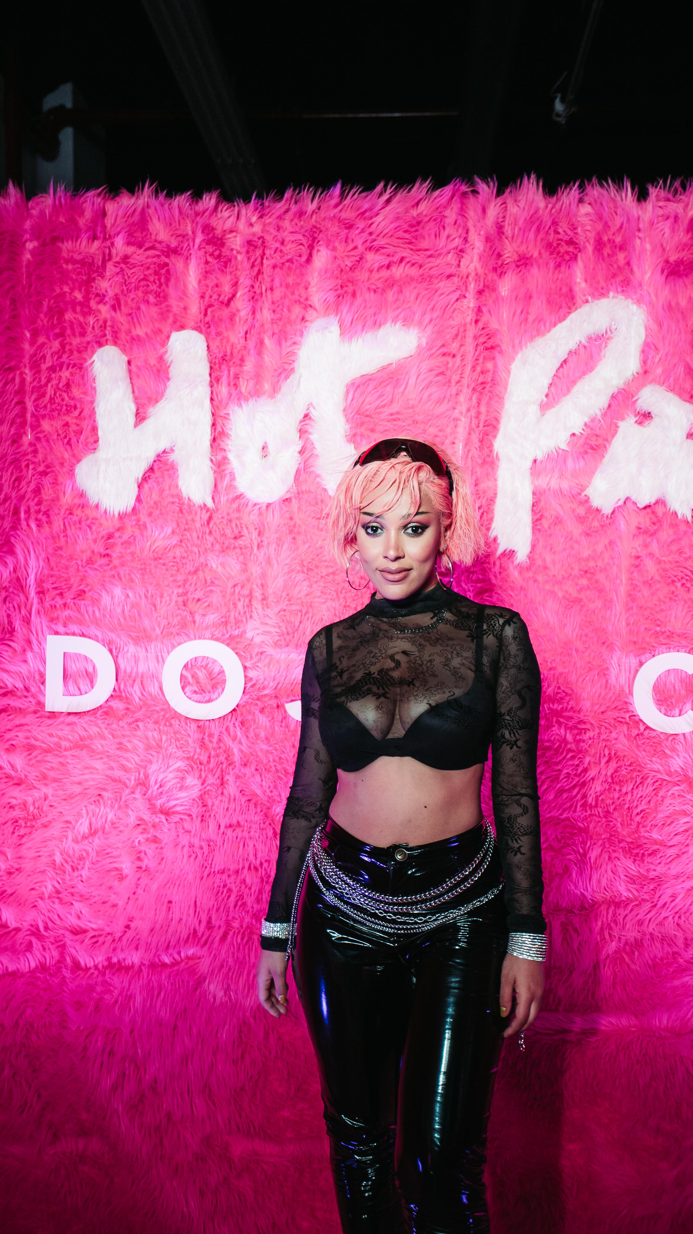 Doja Cat posing in front of a hot pink fur wall at her Hot Pink event at LUME Studios