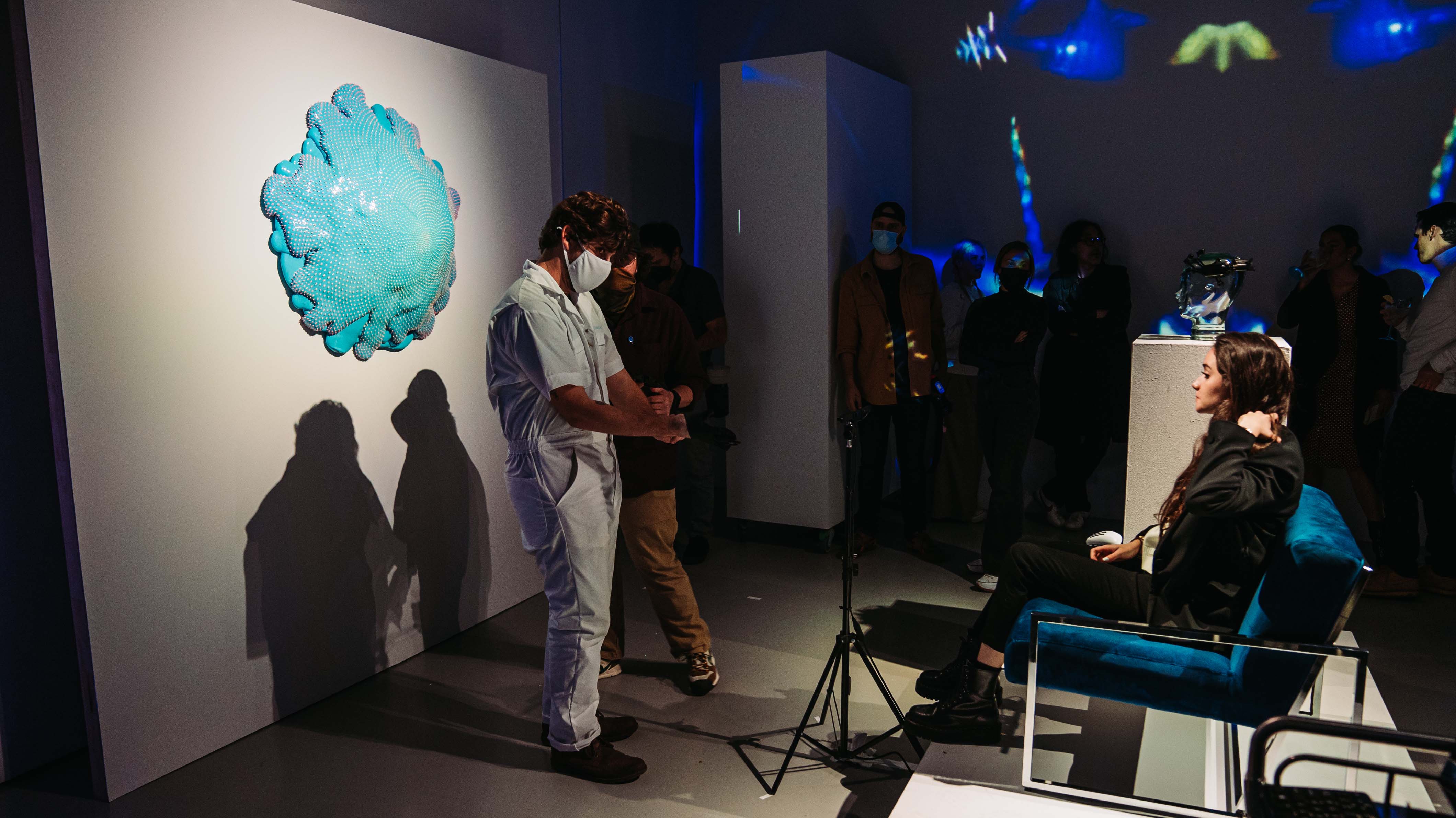 Dan Lam's teal drip sculpture on a white wall as guests mingle at the Bombay Sapphire event