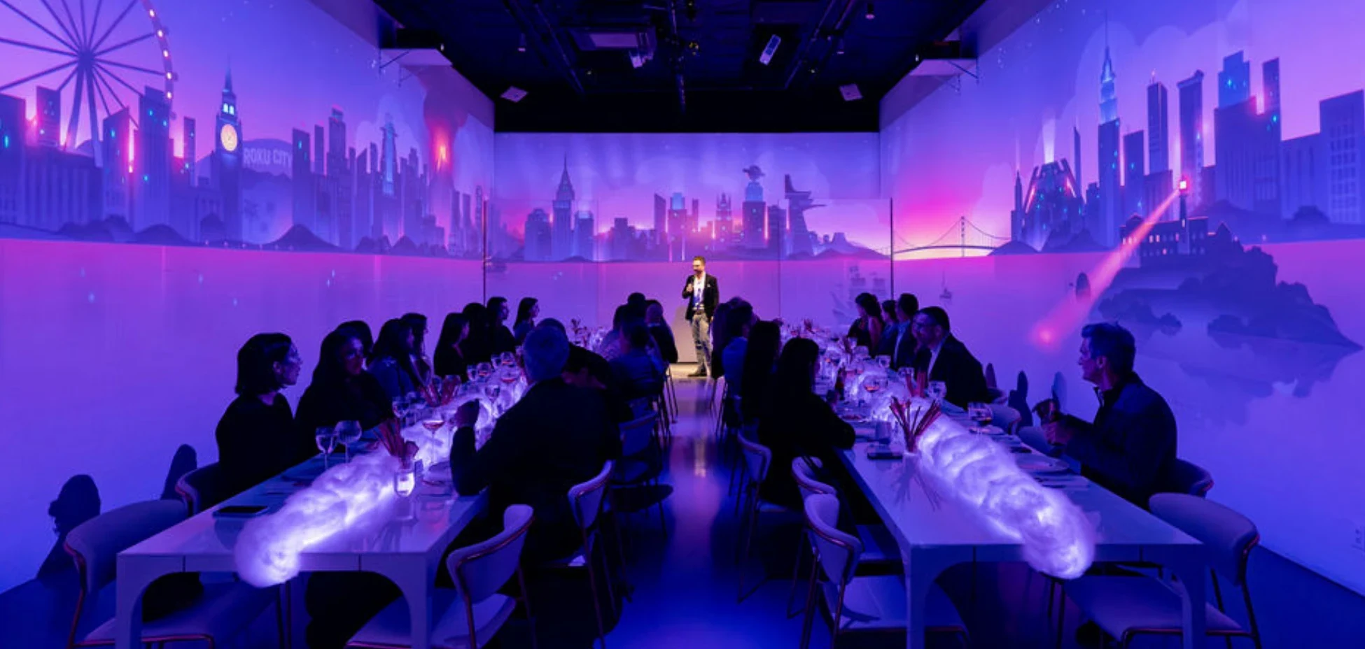 Roku executive dinner at LUME Studios, two long tables under the projected Roku City skyline
