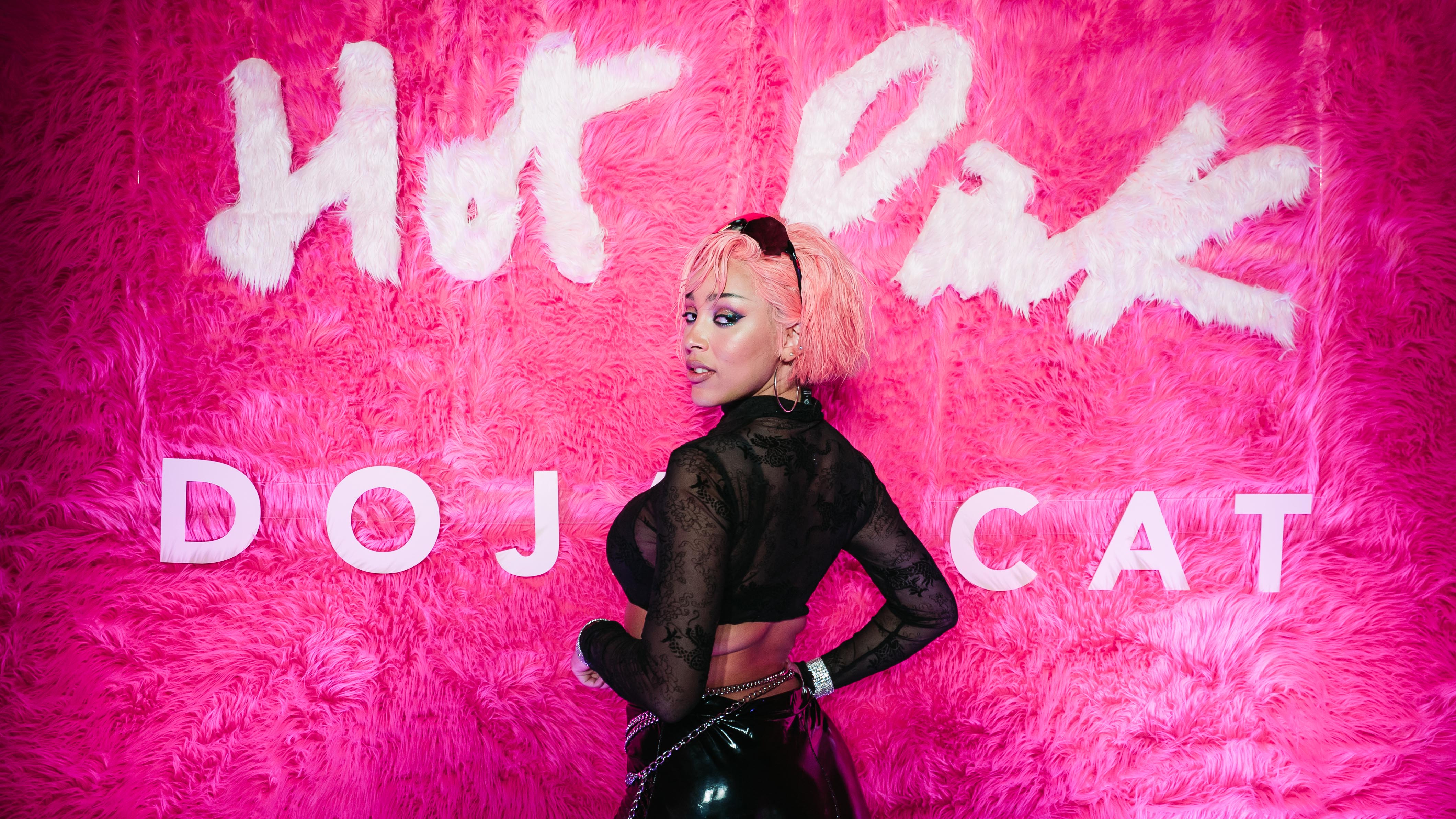 Doja Cat glances back over her shoulder beneath the white fur Hot Pink lettering.