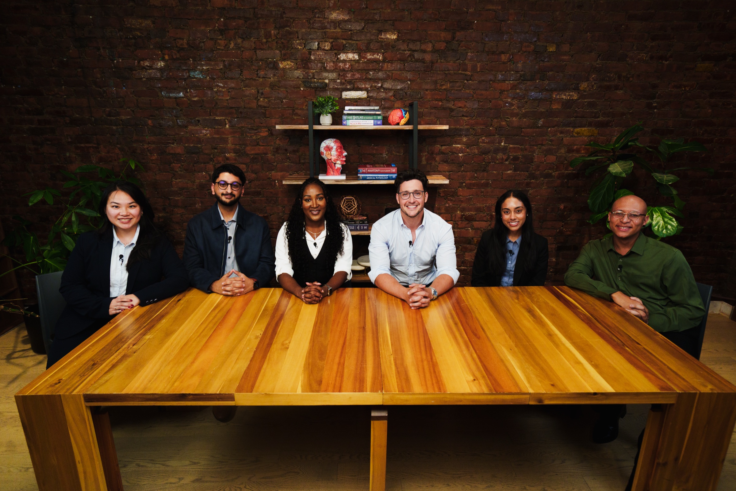 Doctor Mike and five healthcare students behind the podcast table against exposed brick in LOFT 4 at LUME Studios in Tribeca.