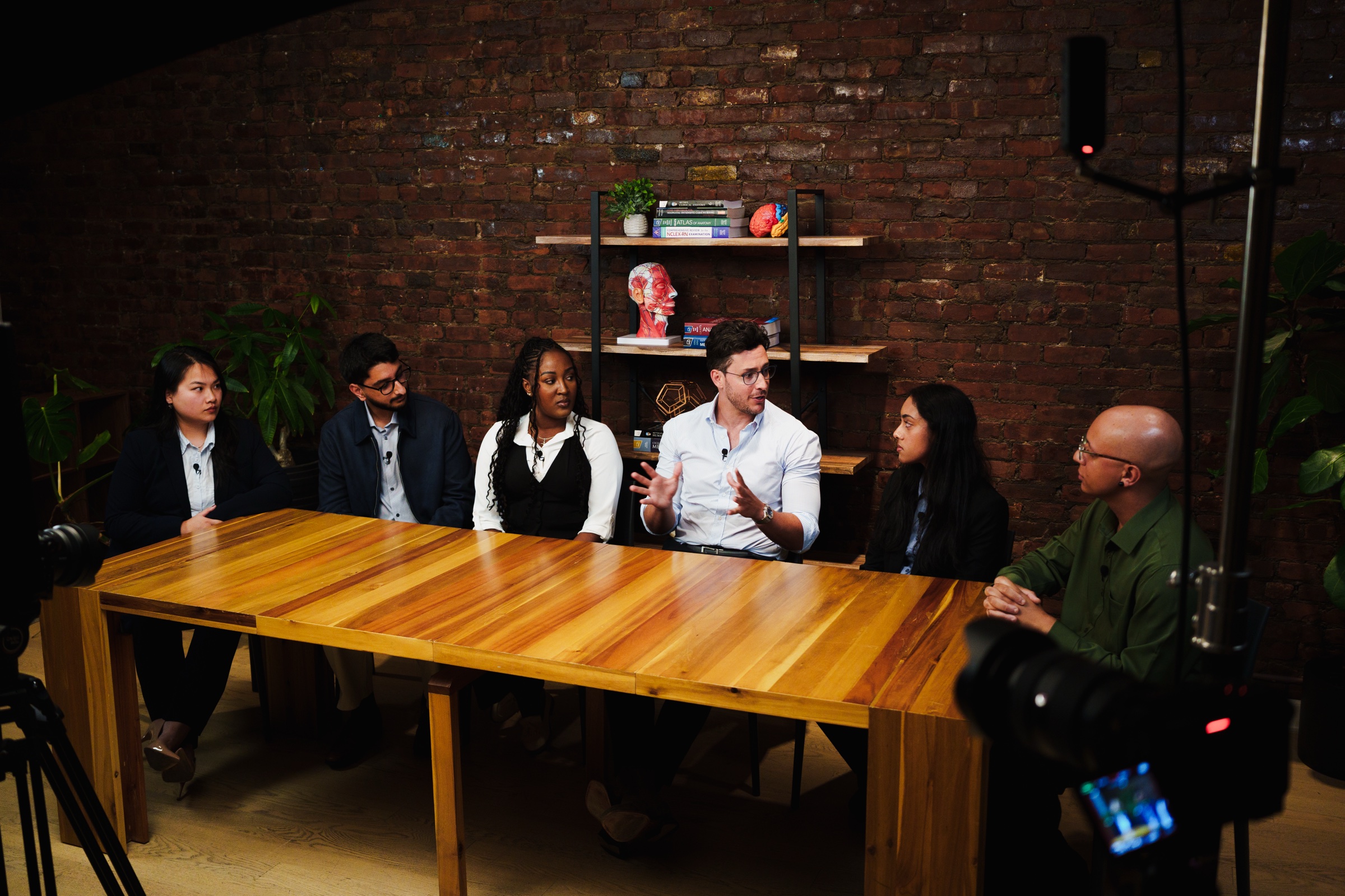 Doctor Mike speaks at the center of the long wooden table with the five students on either side.