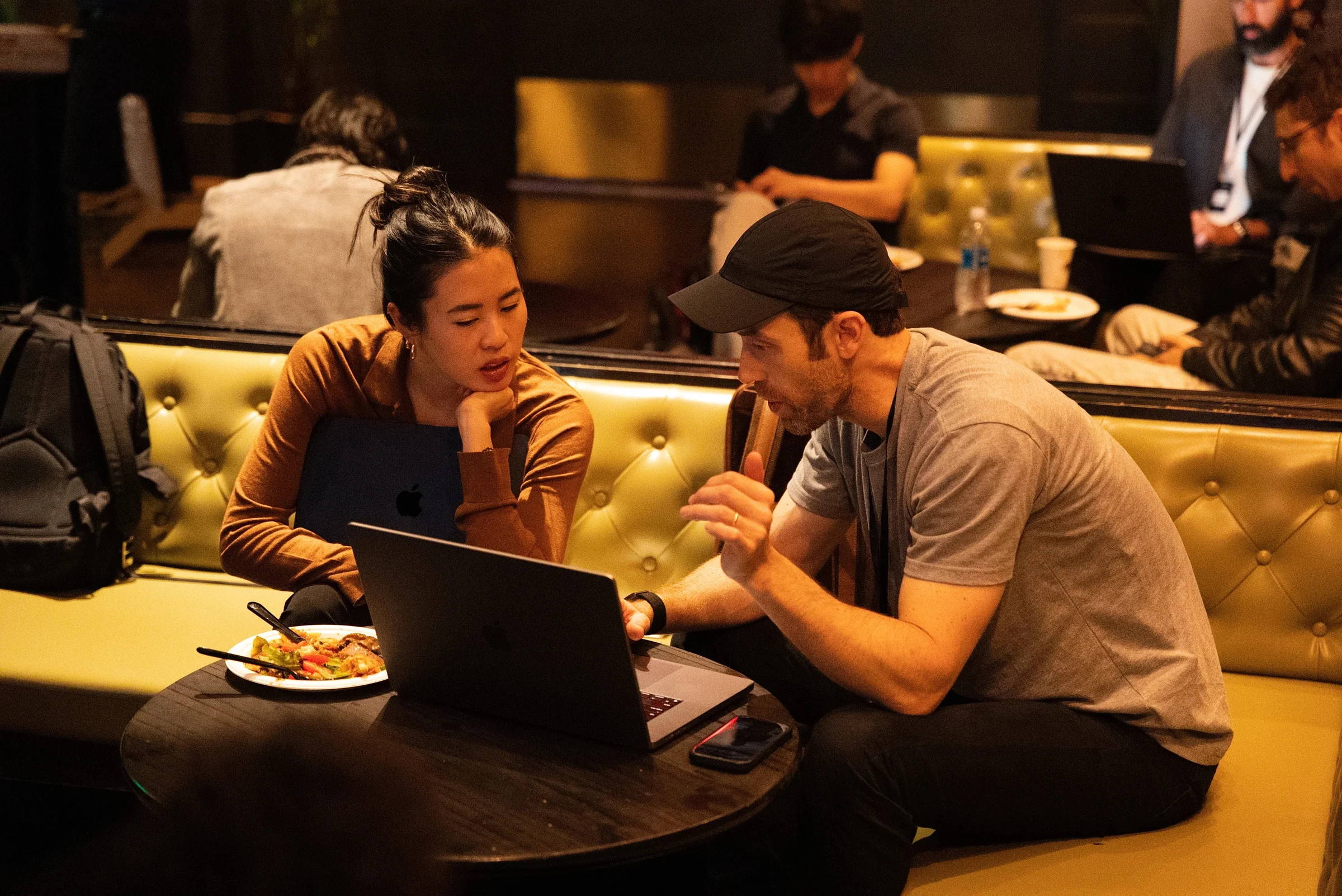 Two attendees work through ideas on a laptop in the Webster Hall lounge between sessions.