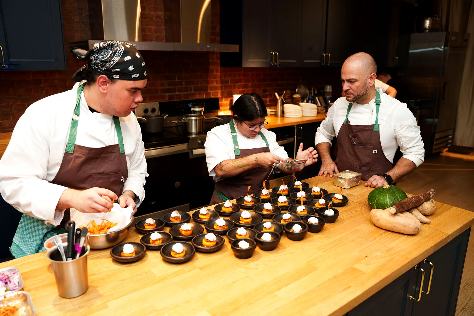 Chefs plating a tasting course at the Loft 4 kitchen island at LUME Studios