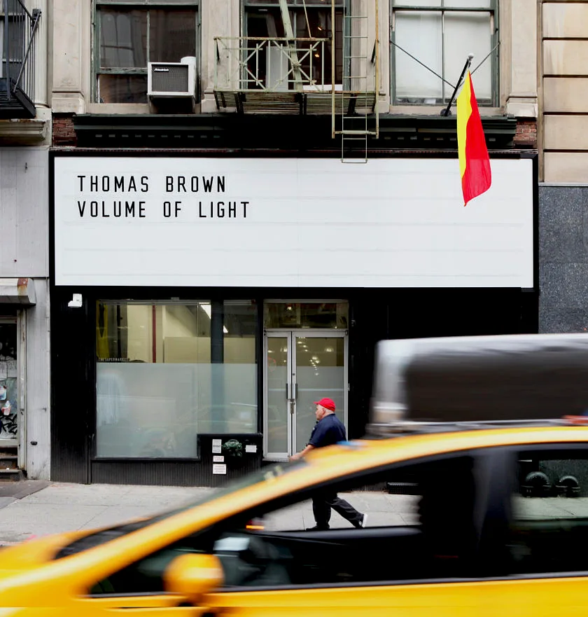 393 Broadway marquee and storefront from across Broadway with a yellow cab passing