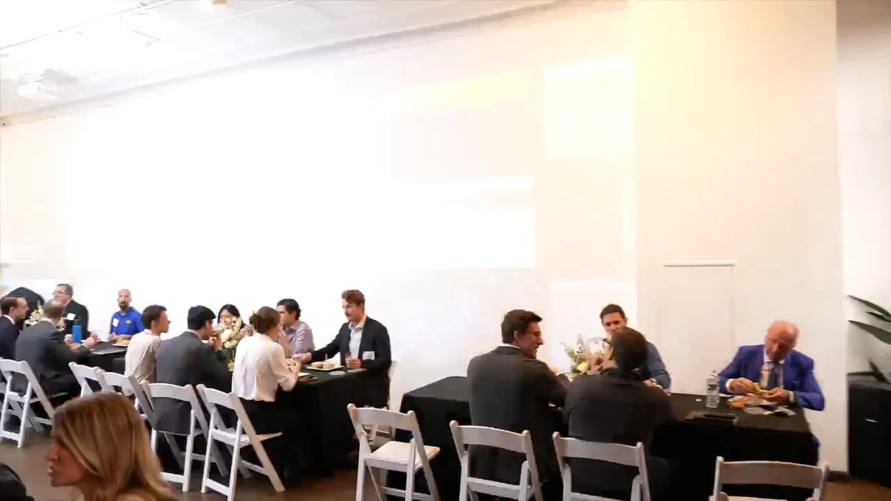 Summit guests at a catered lunch at long black tables in Loft 2 at LUME Studios, between sessions of the MEI+ Summit 2026.