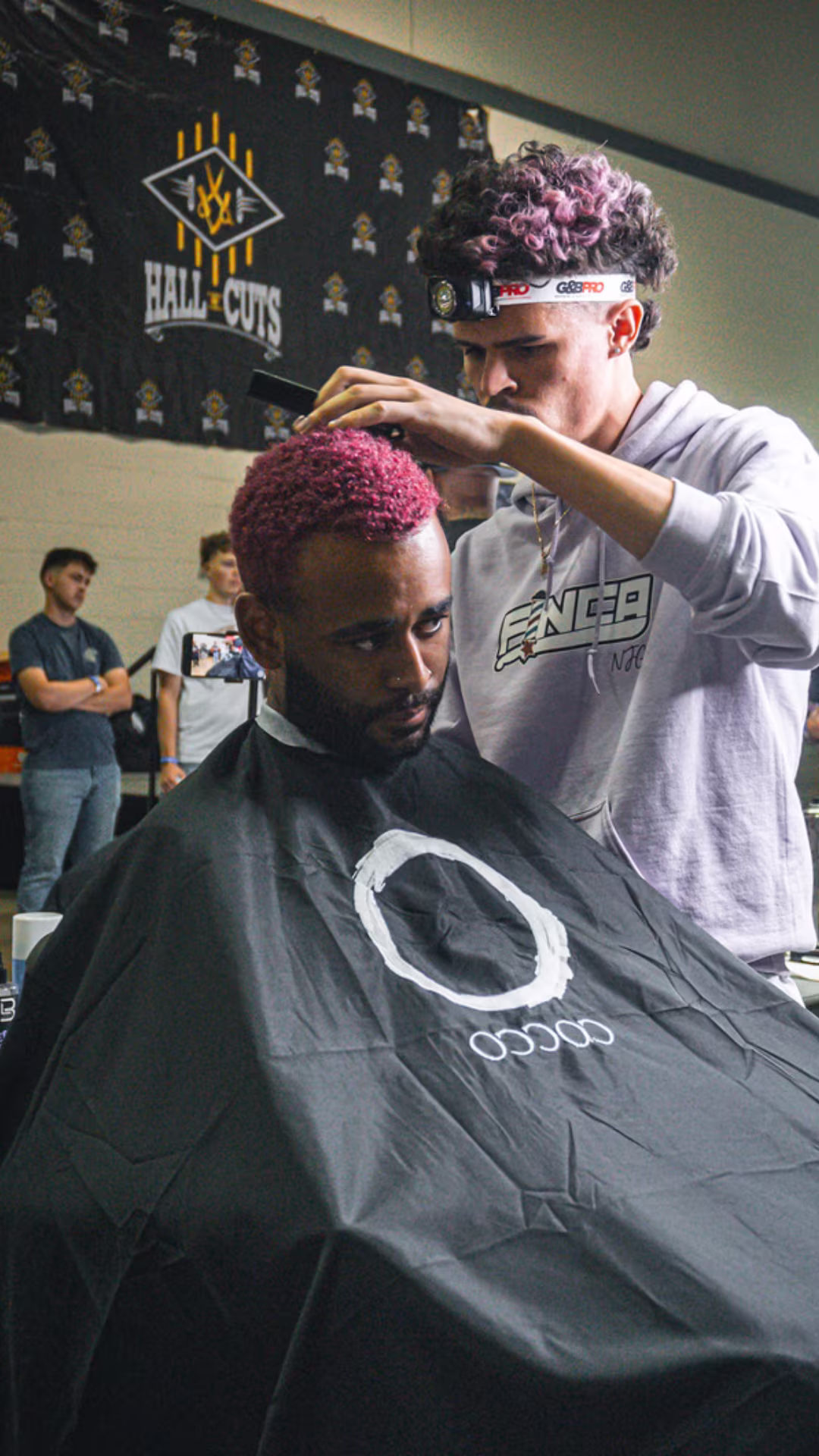 Live barber battle at the Hall of Cuts Akron Barber Tradeshow featuring professional barbers competing on stage for cash prizes, trophies, and national recognition