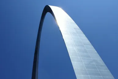 Upward view of the Gateway Arch against a clear blue sky.