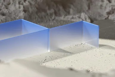 Transparent blue acrylic wall segment standing on sandy ground with rocks in the background.