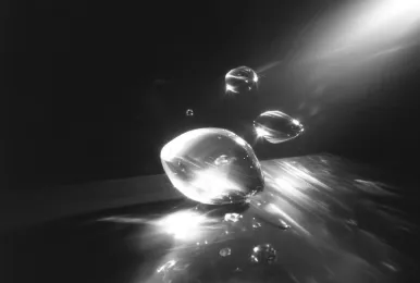 Close-up of glowing water droplets reflecting light in a dark environment.