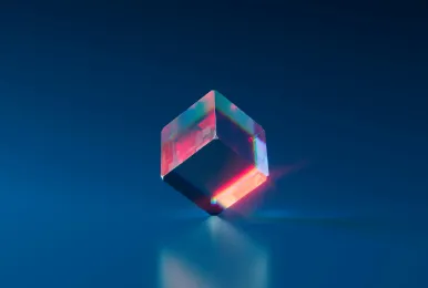 Transparent glowing cube with pink and blue light reflections on a dark blue surface.
