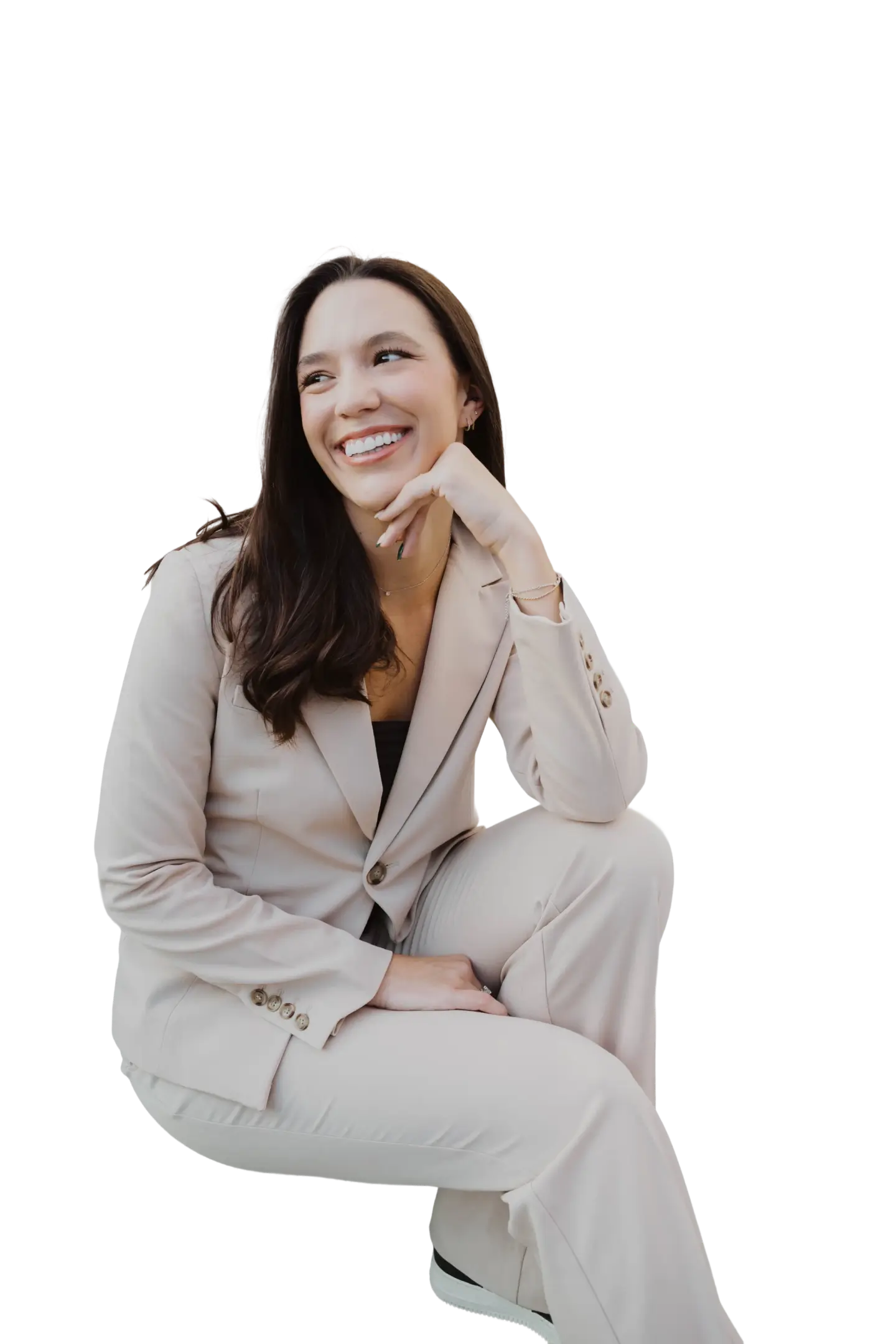 Smiling woman with long dark hair wearing a beige business suit sitting with one hand resting on her chin.