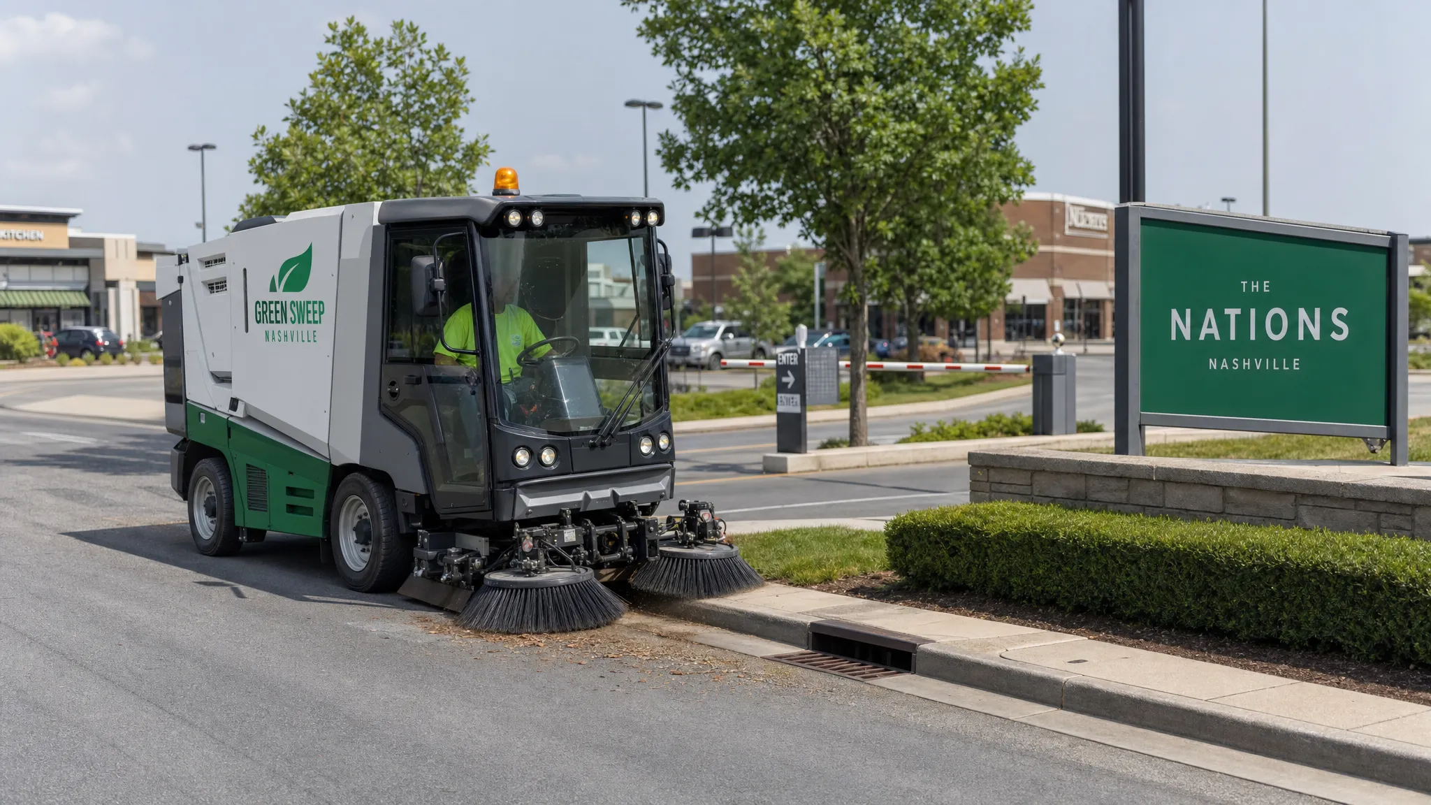 A street sweeper cleaning the curb line of a Nashville commercial property, with clear drive lanes, storm drain inlets, and a parking lot entrance visible in the background.