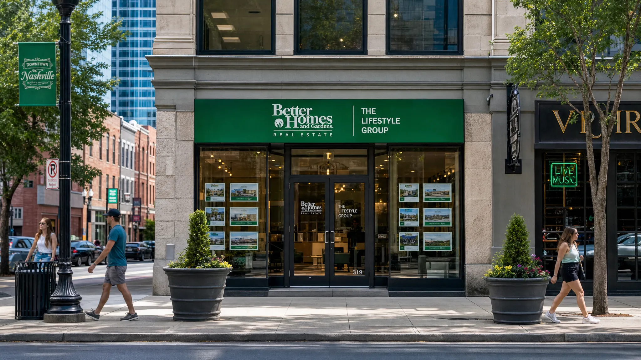 A downtown Nashville storefront seen from across the street, with swept sidewalks, clear curb lines, planters, glass doors, and pedestrians passing by a well-maintained commercial block.