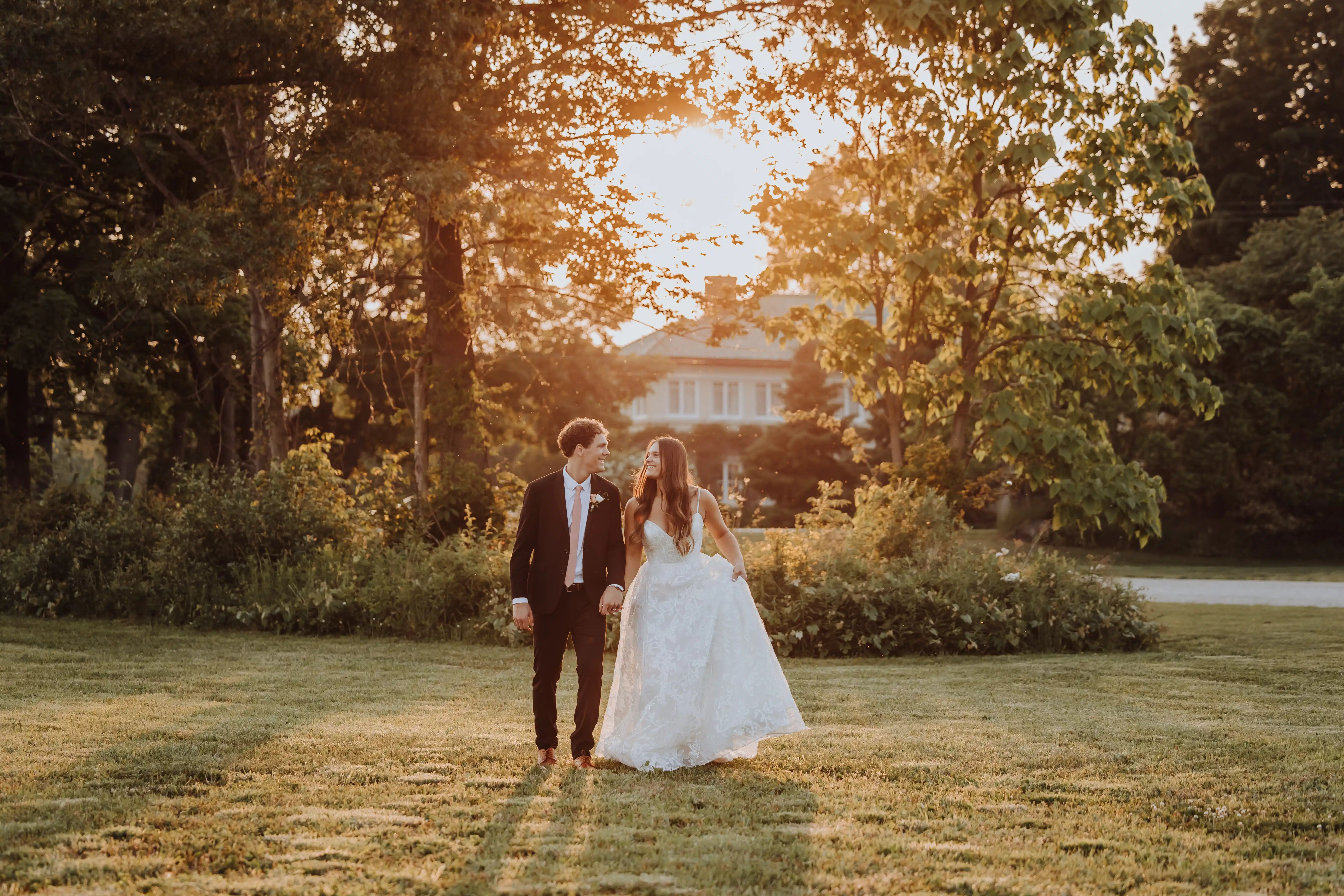 Wedding couple holding hands in the gardens of Belvedere Estate at golden hour, Saugatuck Michigan