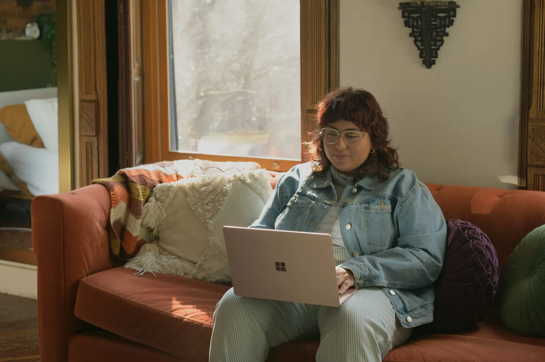 A woman sitting on a couch while operating her laptop.