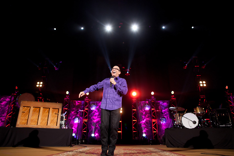 Nazareth performing standup comedy on stage under purple lighting