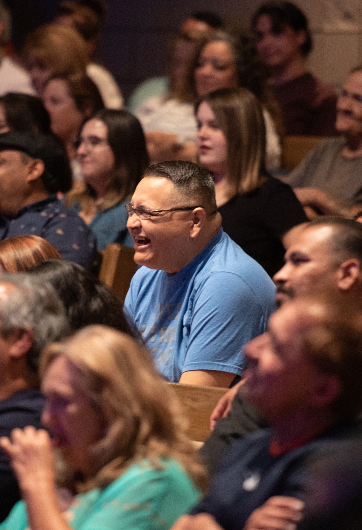 Smiling Nazareth Church attendees enjoying a joyful moment during a live service inside the auditorium.