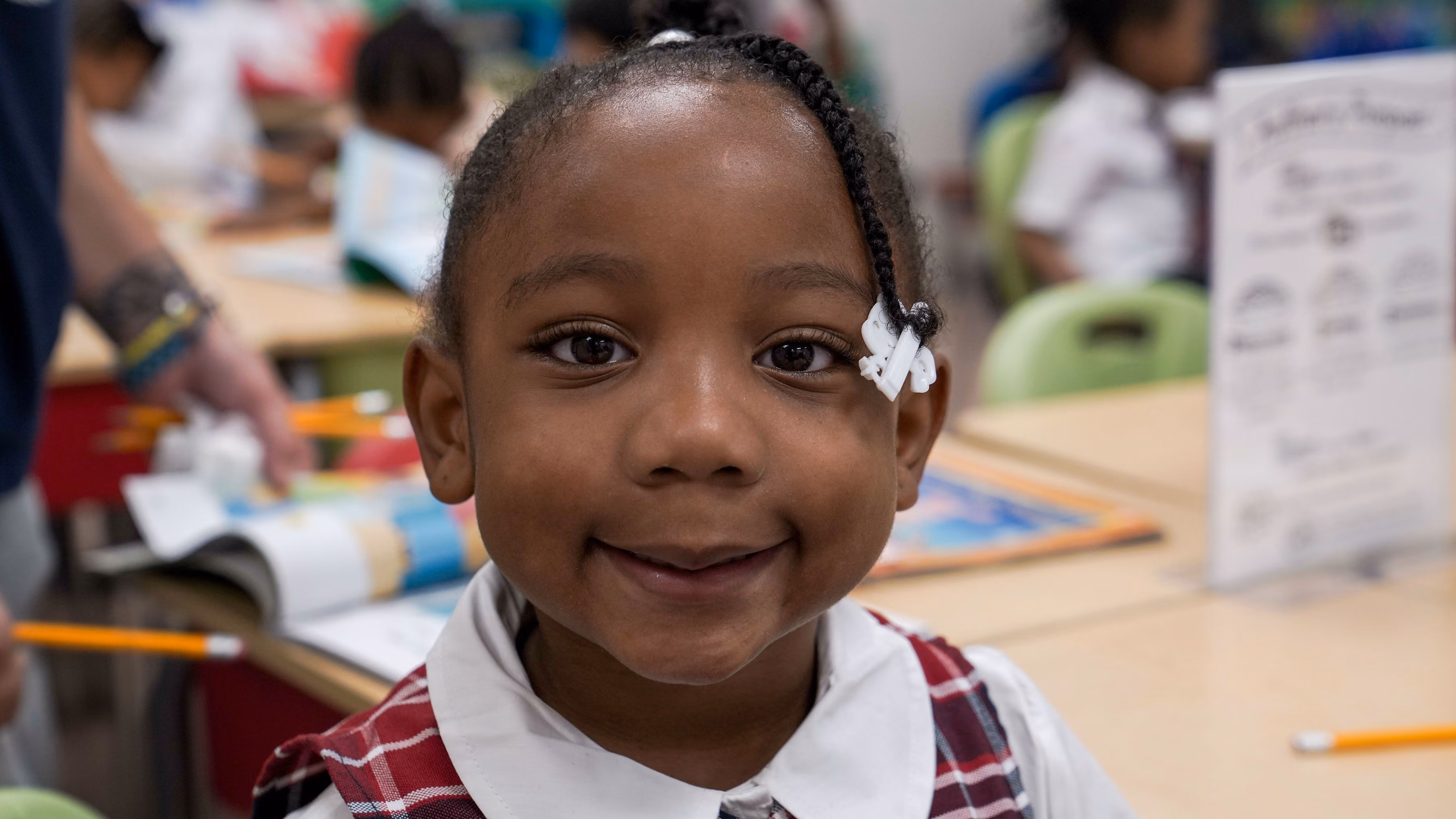 Smiling young student in uniform at classroom desk