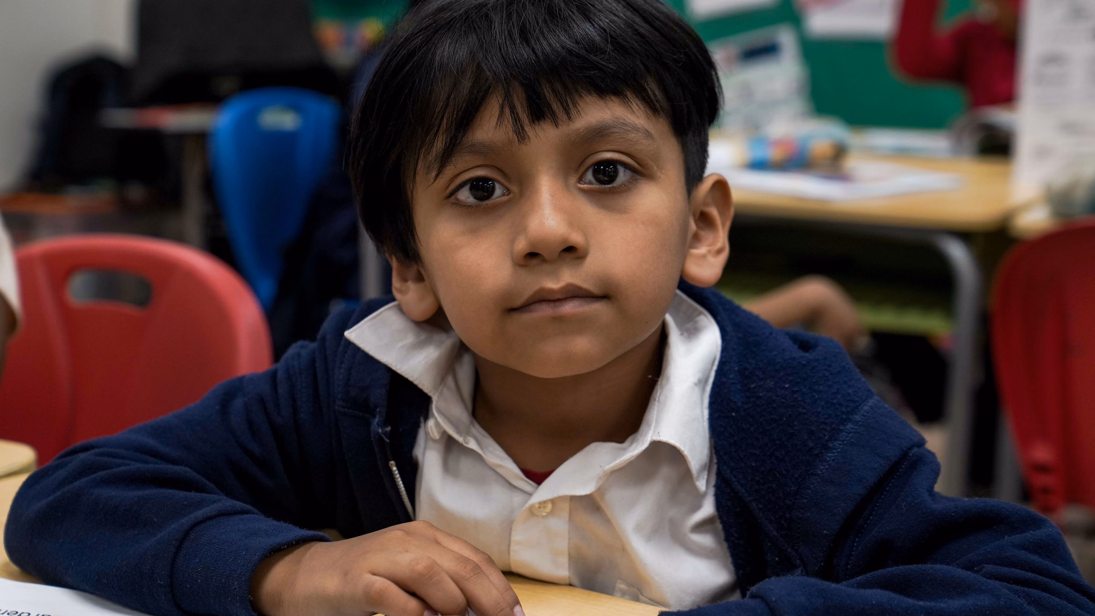 Young student in school uniform sitting attentively at classroom desk