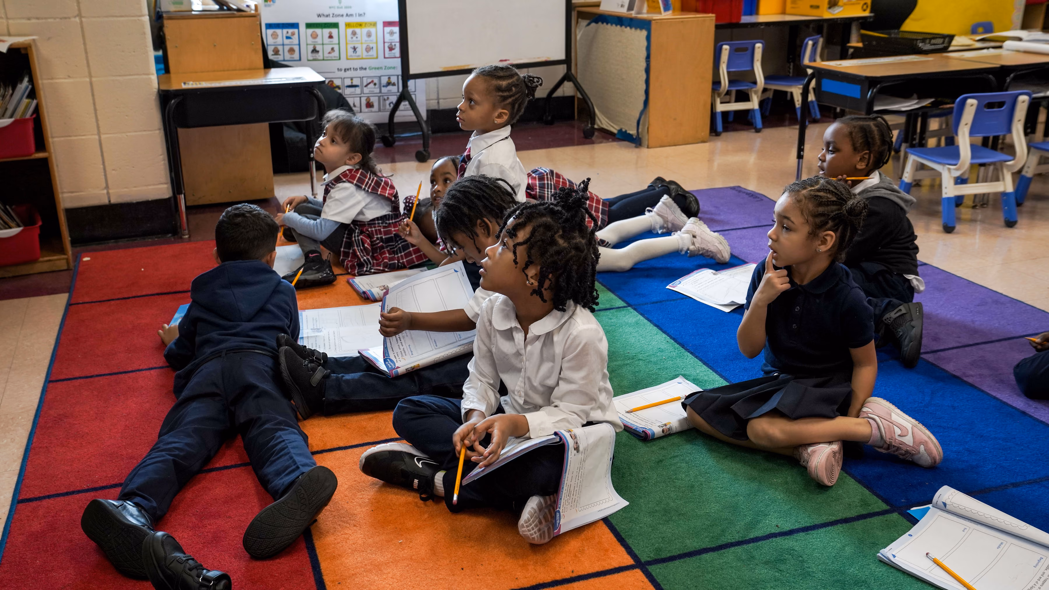 Elementary students in uniform sitting on classroom rug during lesson