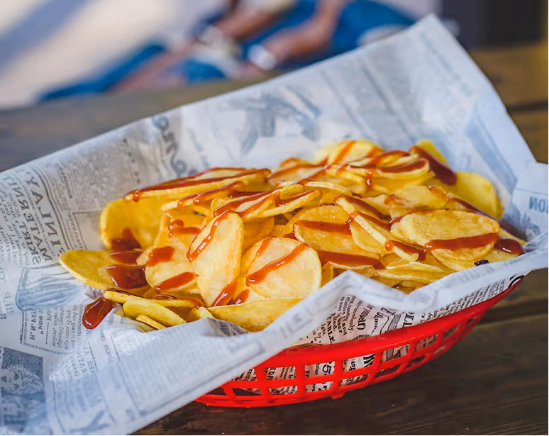 Basket filled with baked potato chips served on a table.
