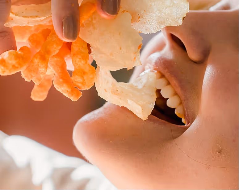 Side view close-up of a person eating baked potato chips.