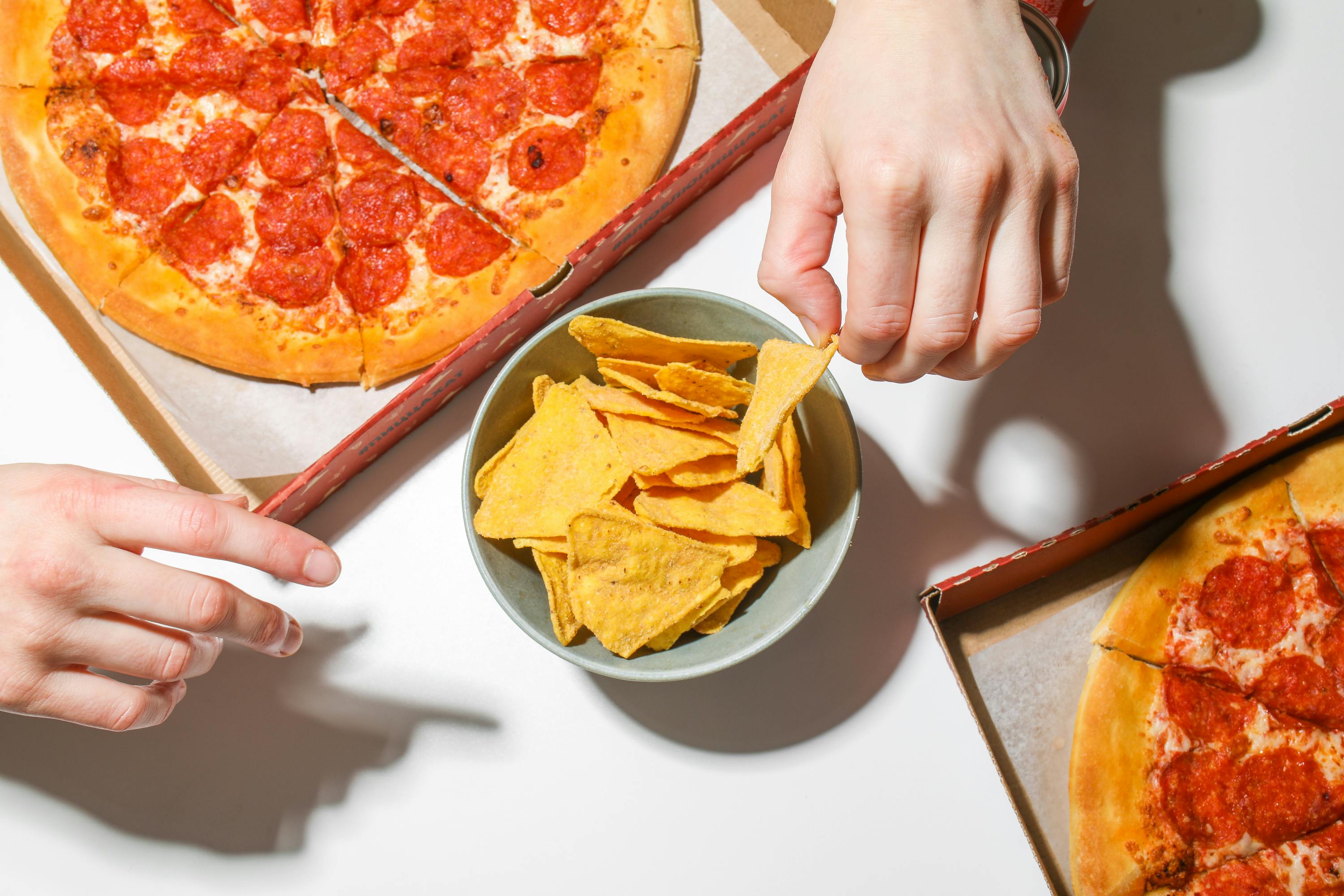 SNAXX baked potato chips served alongside pizza on a table.