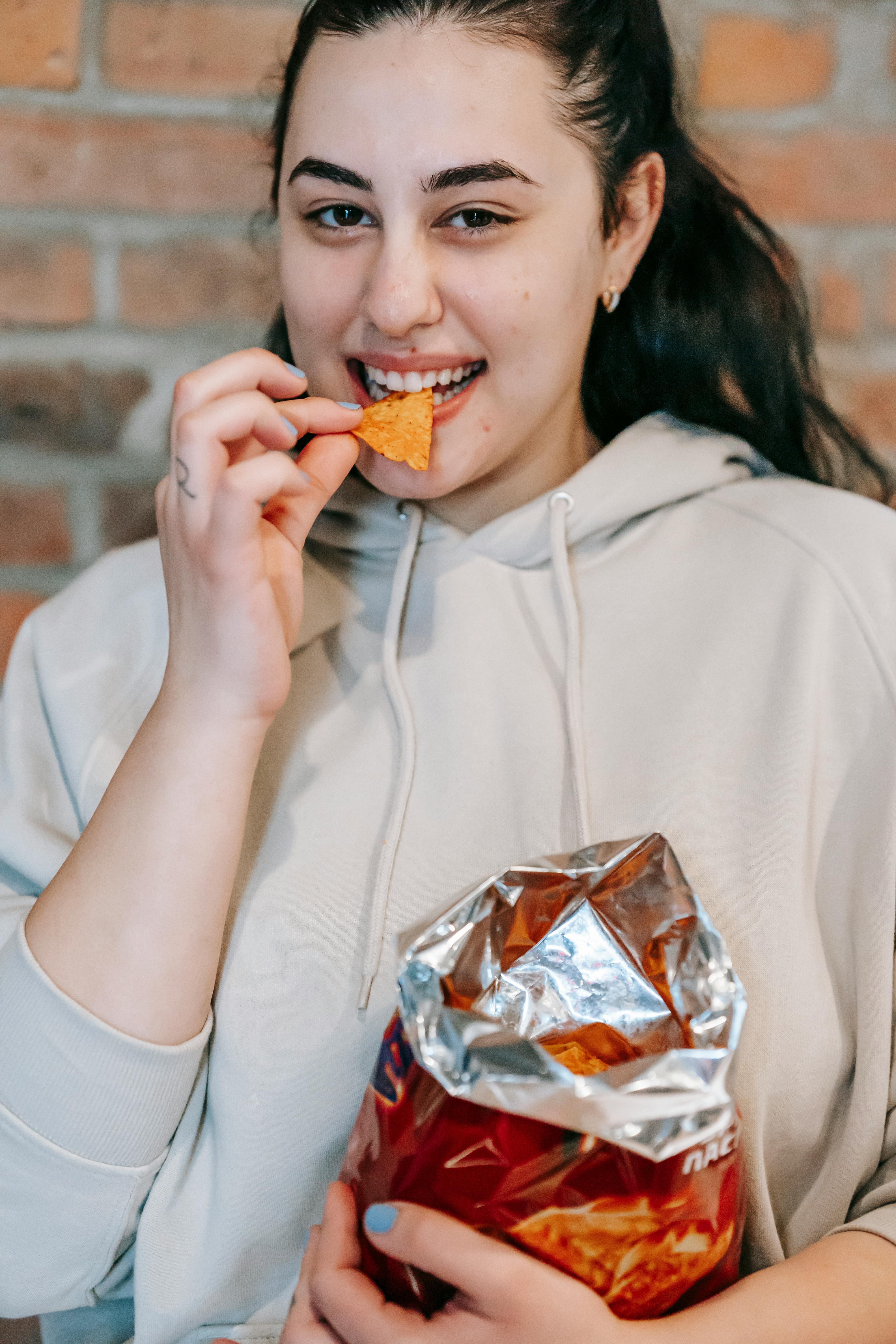 Woman enjoying SNAXX baked potato chips straight from the bag.