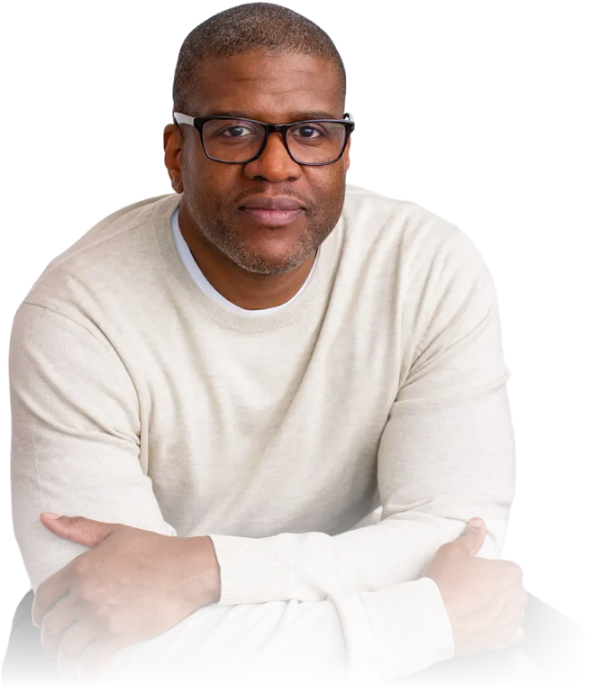 Man wearing glasses and a light beige sweater with arms crossed, looking at the camera.