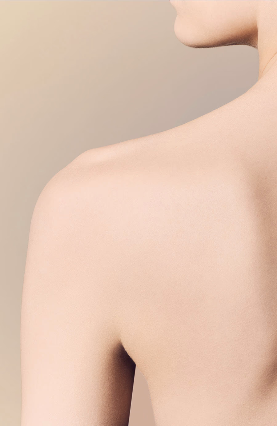 Close-up of a person's bare shoulder and neck against a soft beige background.