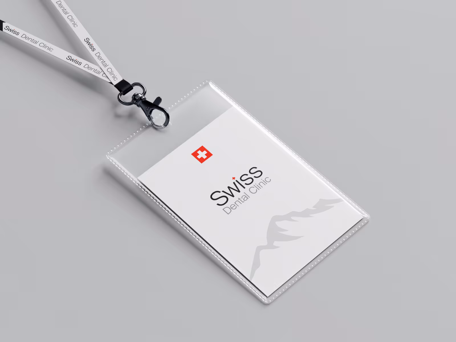 ID badge holder with lanyard displaying Swiss Dental Clinic logo and a mountain outline on a gray background.