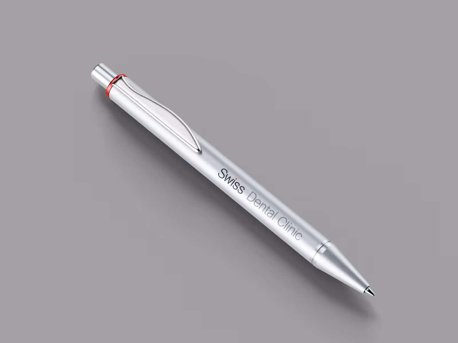 Silver pen on gray background with 'Swiss Dental Clinic' printed on the barrel.