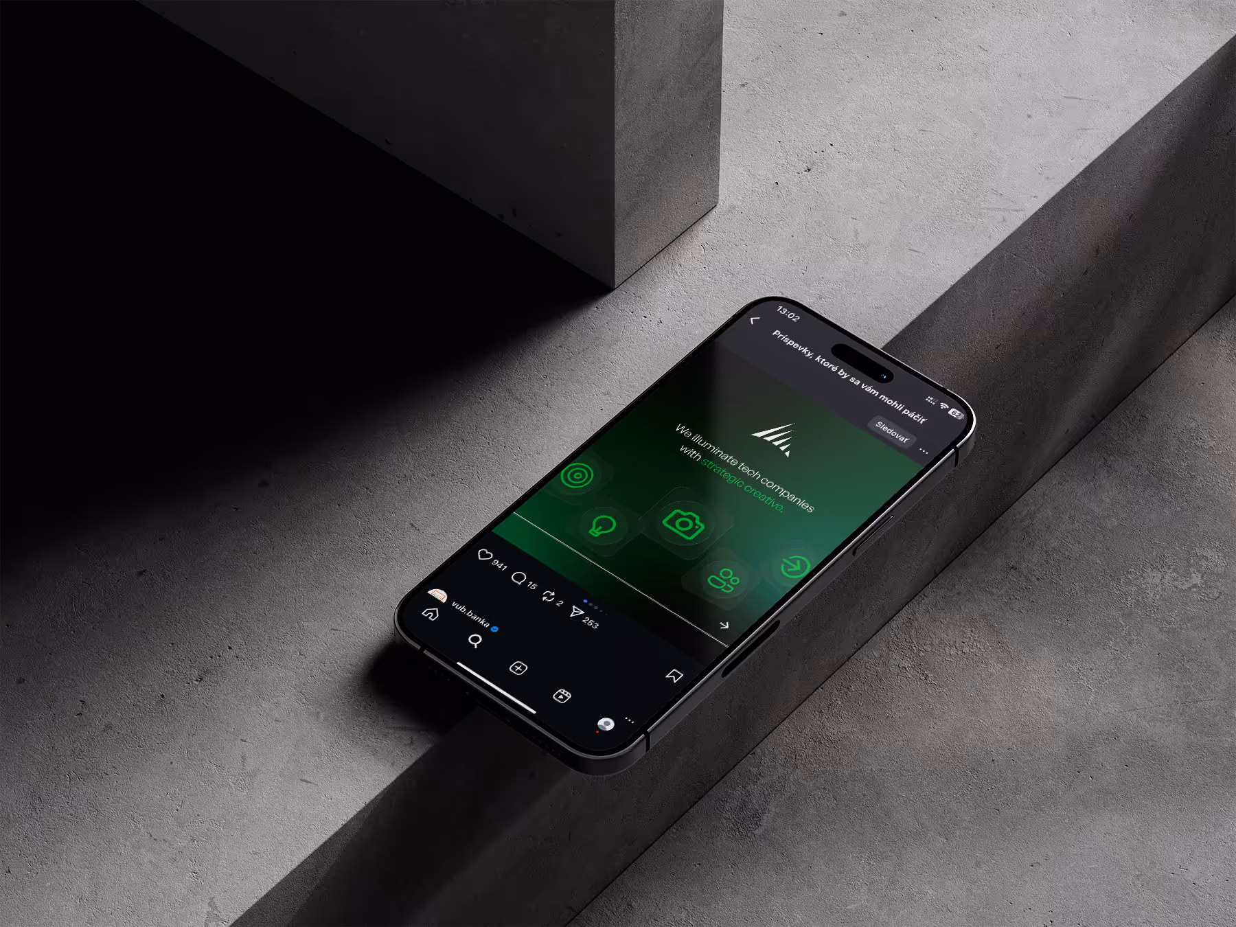 Black smartphone displaying a green-themed social media post on a gray concrete surface with dramatic lighting and shadows.