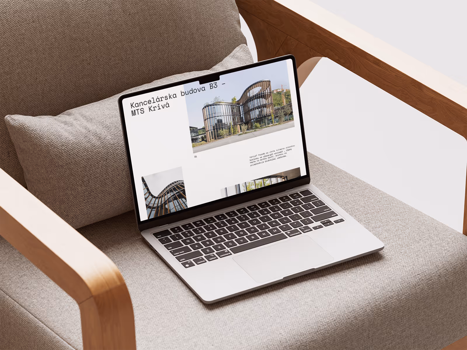 Open laptop on a beige armchair displaying modern office building photos with Slovak text.