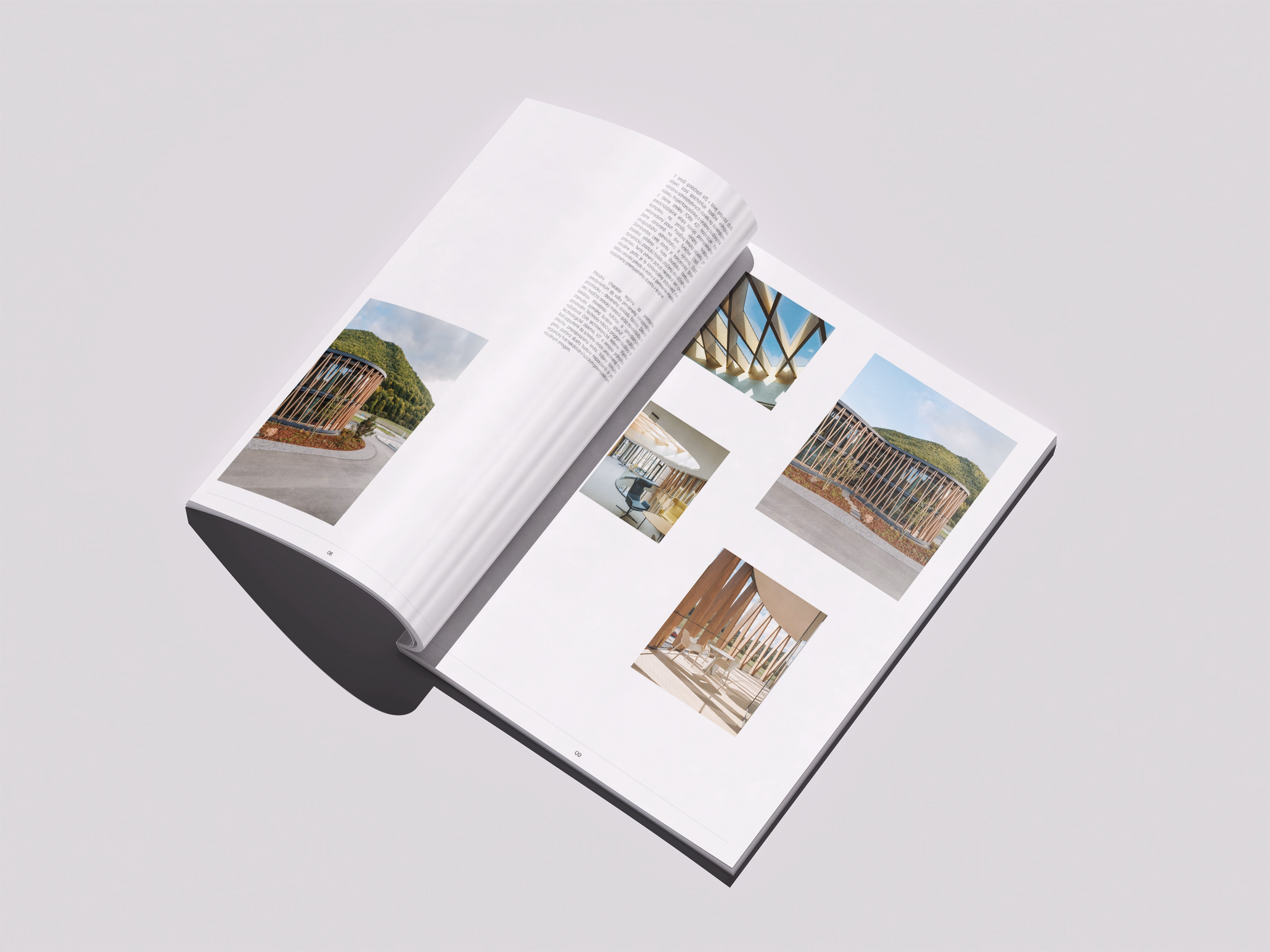 Open magazine laying flat on a gray surface showing architectural photographs and text, featuring images of modern structures with wooden and metal elements against natural backgrounds.