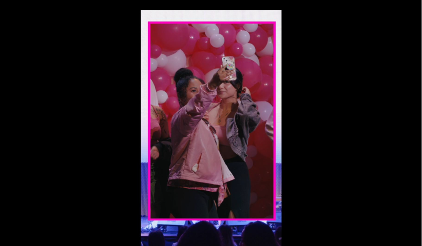 Two young women taking a selfie together with pink and white balloons in the background.